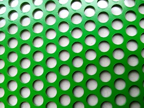 Зеленый порошок покрывая вокруг листа пефорированного отверстием